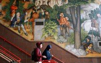 Two students walk down steps past a historical mural at George Washington High School in San Francisco.