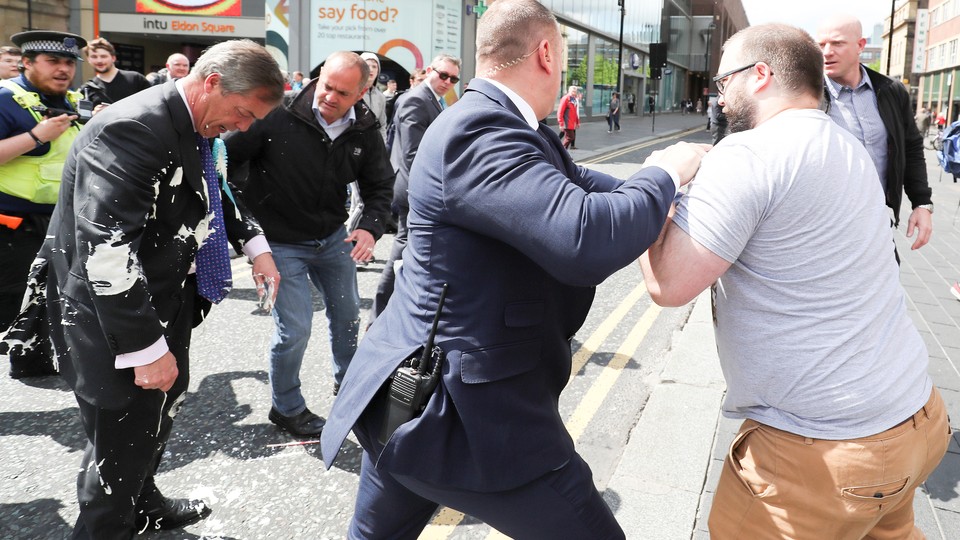 A security guard pushes back a man after he dumped a milkshake on Nigel Farage.