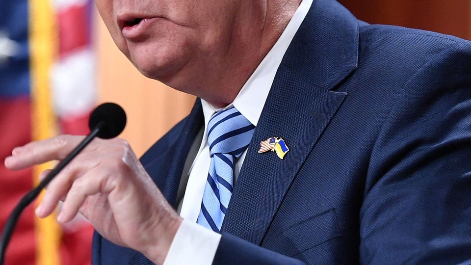 Lower half of Lindsey Graham's face above a U.S.-Ukraine lapel pin on a navy suit jacket