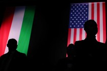 An image of two men standing in front of a U.S. flag and a Hungarian flag