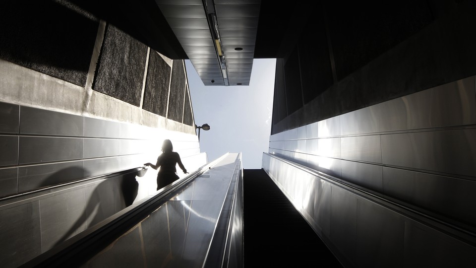 A woman walks down the stairs to the entrance of a metro station.