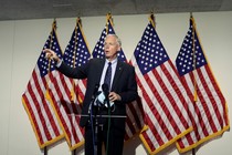 Ron Johnson talks at a press conference in front of American flags.