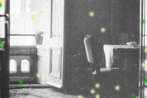 Black-and-white photo of table and chair near open balcony doorway with green and yellow dots