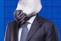 A businessman in a suit is shown wearing a donkey mask.