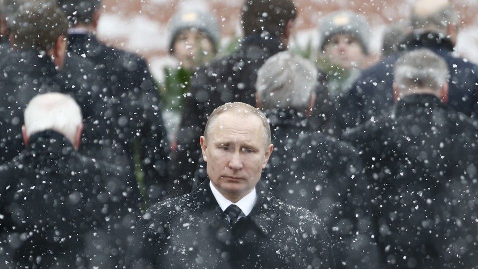 Russian President Vladimir Putin stands in the snow at a wreath laying ceremony.