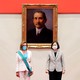 Nancy Pelosi, wearing a white pantsuit with a turquoise sash, standing with Taiwan’s president in front of a painting of Sun Yat-sen