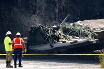 A photo of construction workers surveying highway damage