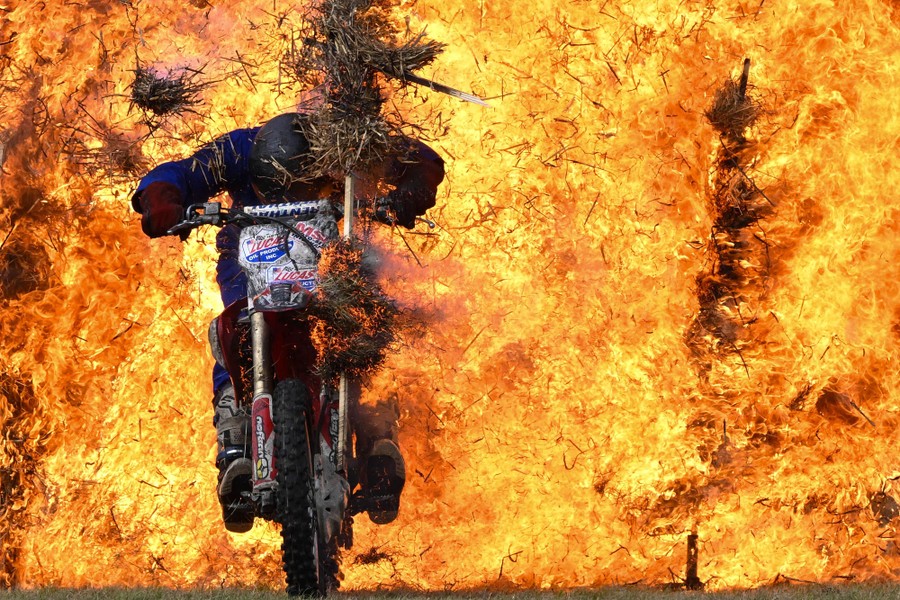 A stunt person rides a motorcycle through a wall of flames.