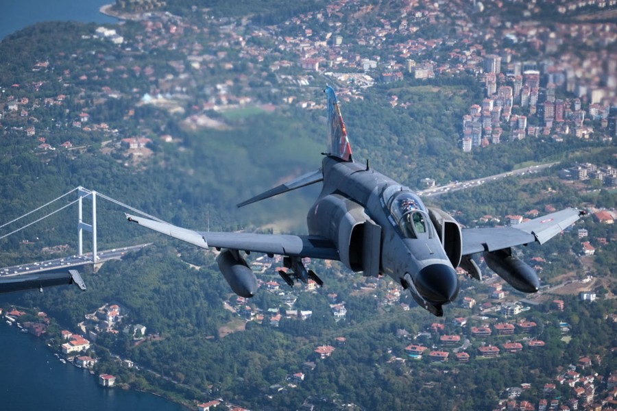 A Turkish fighter aircraft is seen in the air above a city.