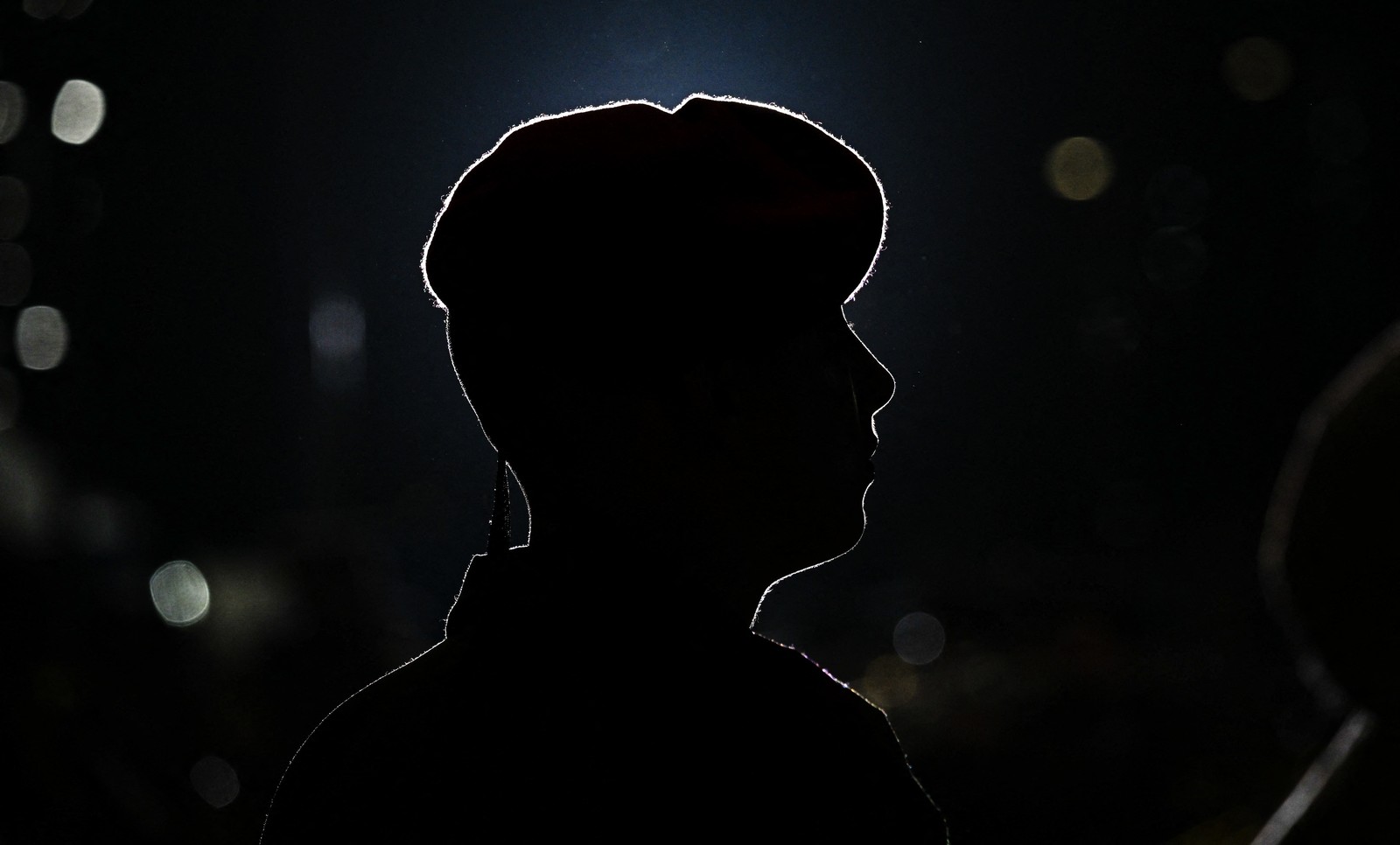 A soldier wearing a beret, seen in silhouette