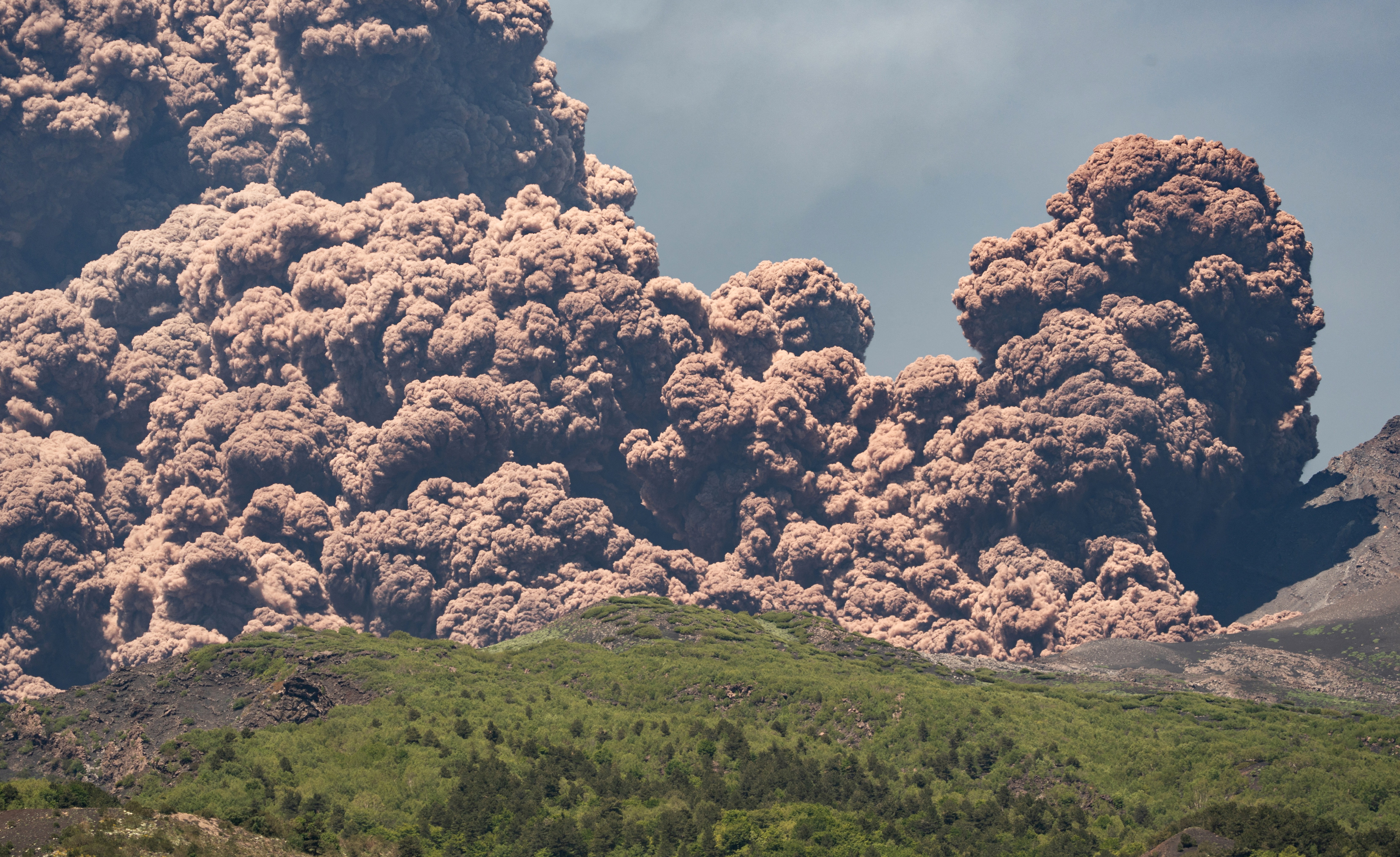 Plumes of volcanic ash rise from a volcano.
