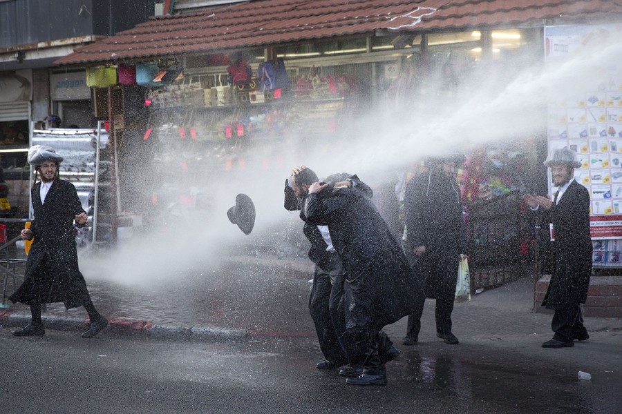 Ultra-Orthodox Jews are hit by a police water cannon during a protest against Israeli army conscription in Jerusalem on March 15, 2017.