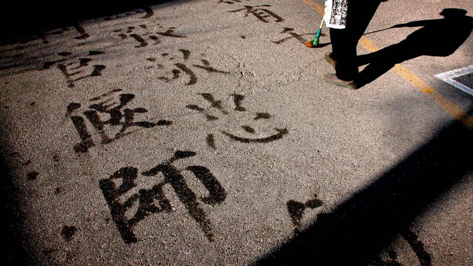 A man writes Chinese characters on a footpath using water and a brush in central Beijing.