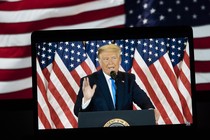 A TV image of former President Donald Trump speaking in front of U.S. flags