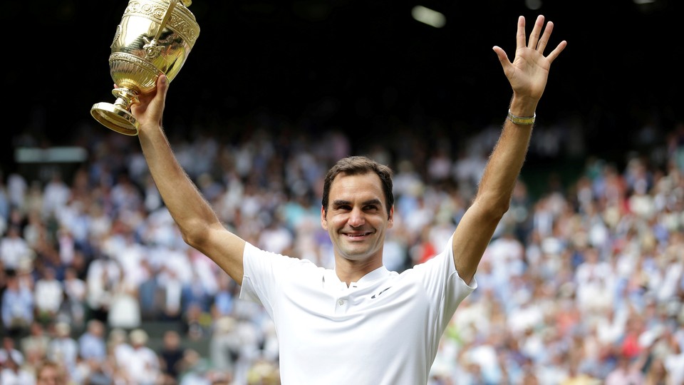 Roger Federer shows off his Wimbledon trophy.