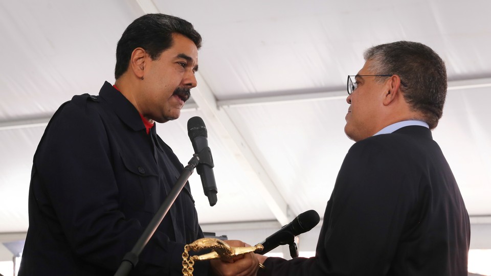 Maduro presents Minister for Education Elias Jaua with a replica of the sword of national hero Simon Bolivar during a ceremony in Caracas on July 26, 2017.