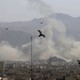 Birds fly over Tehran, with clouds of smoke visible in the background