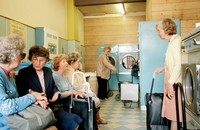 A group of older women chatting in a retro-looking laundry shop