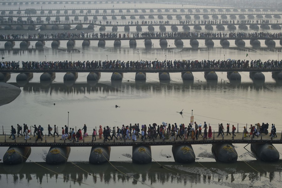 People walk across some of at least seven pontoon bridges over a river.