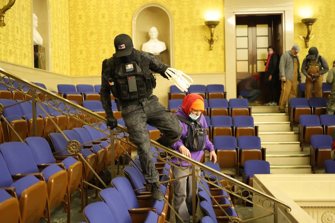A rioter wearing tactical gear carries zip ties in the Senate chamber