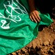 A photo of a man's hand using a green Hamas flag to cover a Palestinian grave.