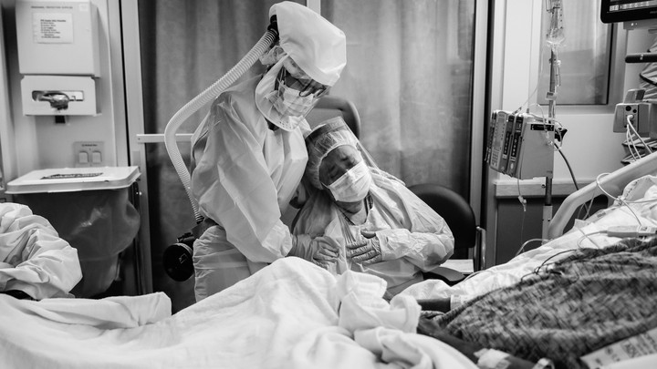 Romelia Navarro is comforted by Michele Younkin, a nurse, while sitting at the bedside of her dying husband.