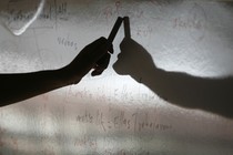 A hand hovers over a dry-erase board, casting a shadow.
