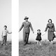 A black and white image of a family holding hands on a hill, with a gap between the son's hand and the father's