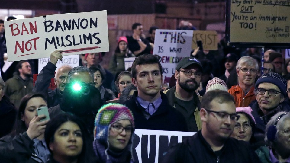 People hold signs with phrases including "Ban Bannon, not Muslims." 