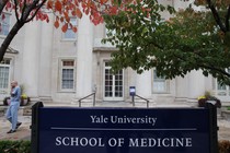 A man in scrubs walks outside the Yale School of Medicine.