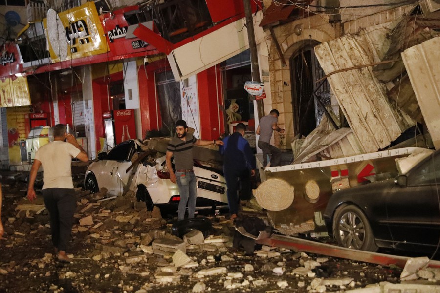 People inspect destroyed buildings.