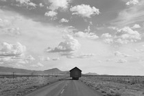 A house being towed on a truck bed along a western road surrounded by desert
