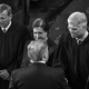 black-and-white photo of Supreme Court justices John Roberts, Elena Kagan, Neil Gorsuch, and Brett Kavanaugh standing in a line, Gorsuch shaking Donald Trump's hand