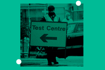 A worker carries an information sign as a coronavirus disease (COVID-19) drive-through testing facility is opened in Bolton, Britain.