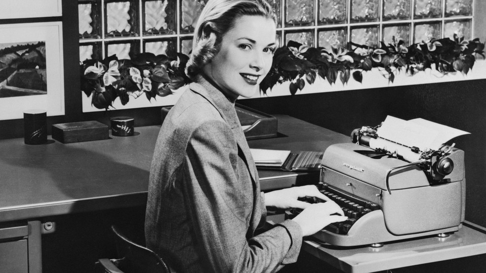 The actress Grace Kelly sitting at a table with a Remington typewriter