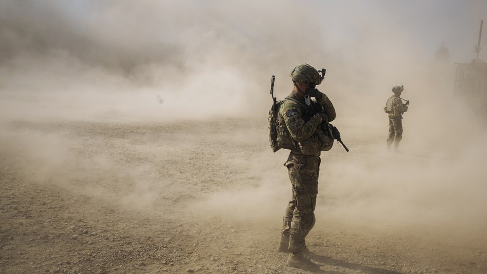 U.S. soldiers cover their faces from the dust blown around by the rotors of a helicopter. 