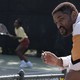 Will Smith sitting by a tennis court where his character's daughter is practicing in "King Richard"