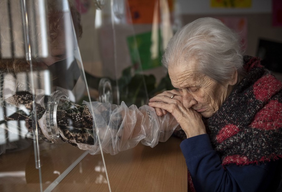An older woman holds the plastic-covered arm of another person.