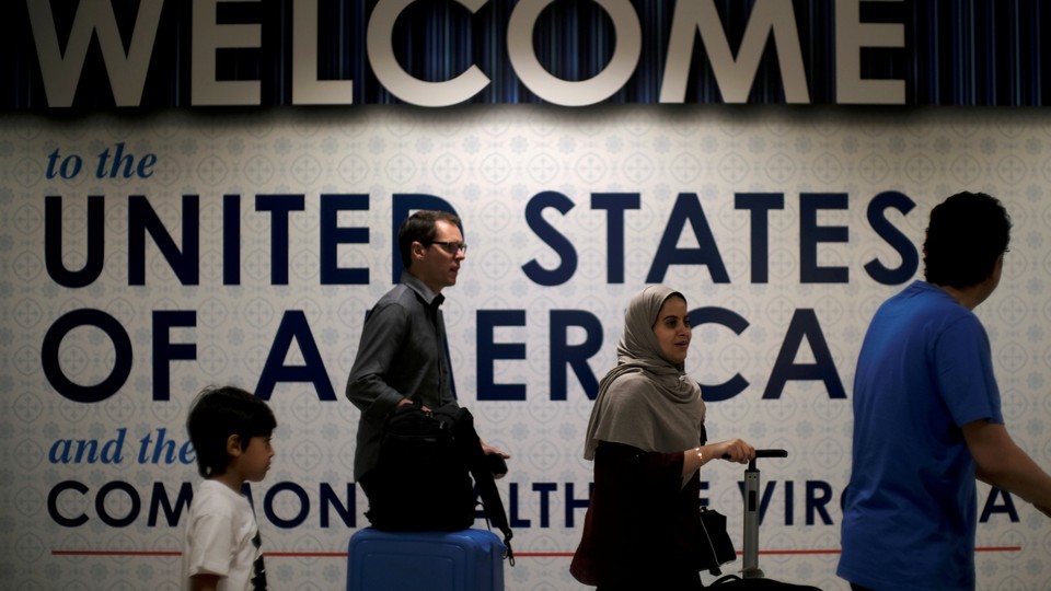 Four people walk past a sign that says "Welcome to the United States"