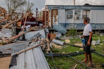 An image of a man in front of a damaged home after Hurricane Ida.