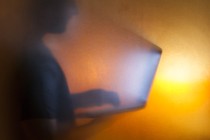 The silhouette of a man looking at a bright computer screen