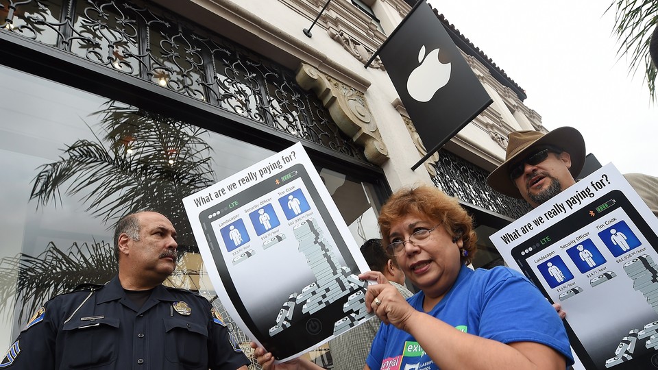 Workers holding signs and protesting in front of an Apple store