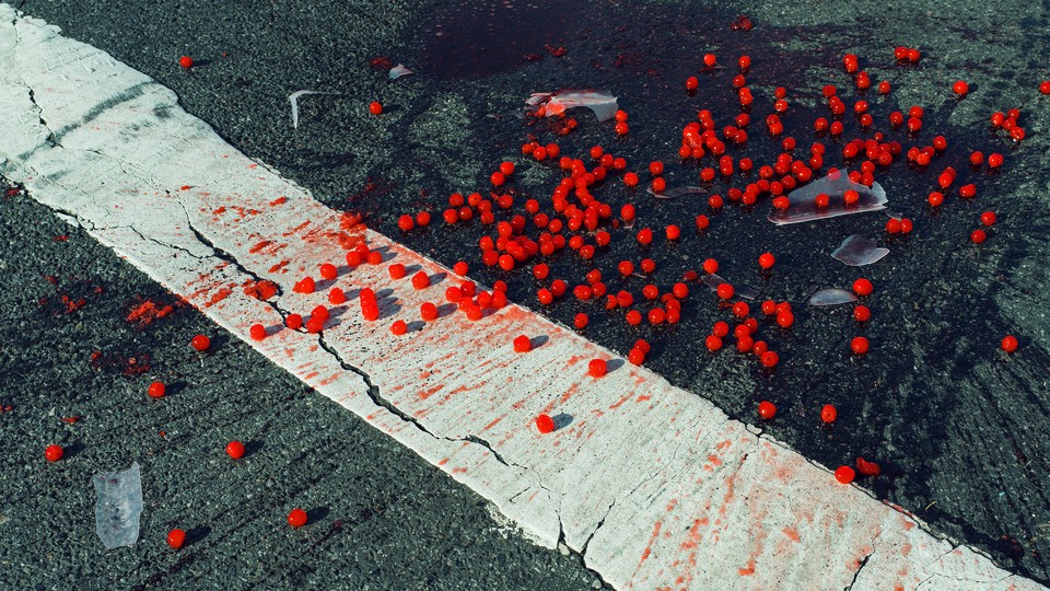 a container of red currants, shattered on the ground in a parking lot