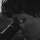 black-and-white photo of person looking into lens of telescope with reflected image lighting up the iris of their eye