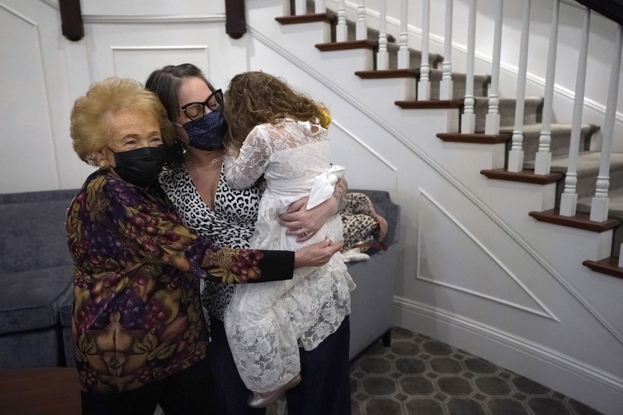A woman hugs her great-niece and her great-great-niece.