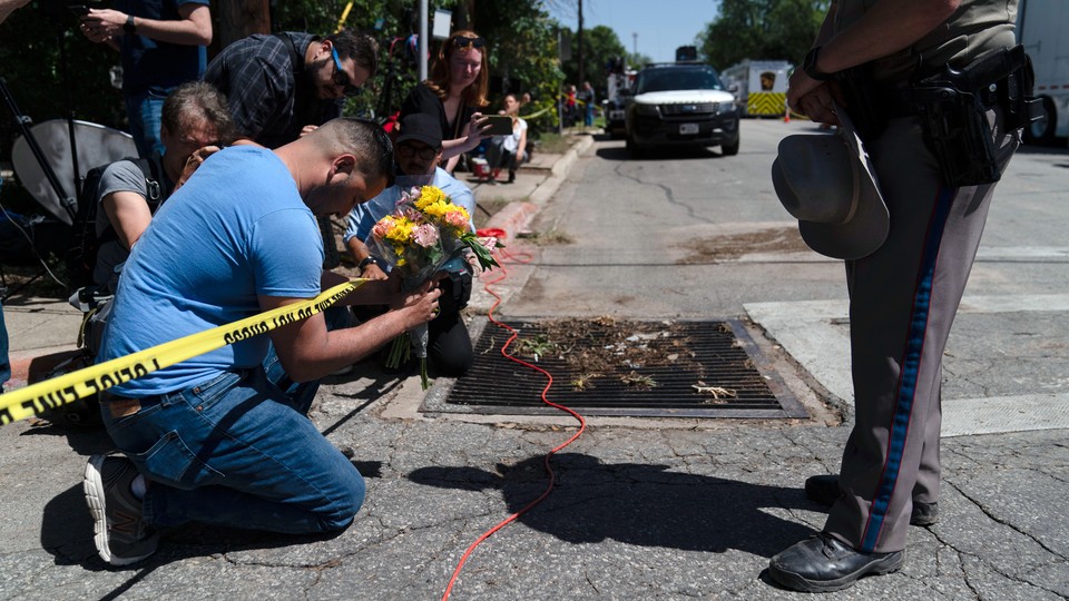 A man praying and holding flowers for the children killed in Uvalde, Texas.