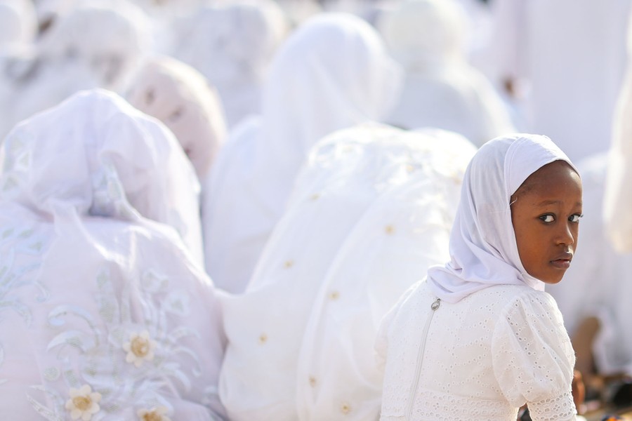 People pray, seated, all dressed entirely in white.