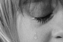 Cropped black-and-white close-up image of a child crying