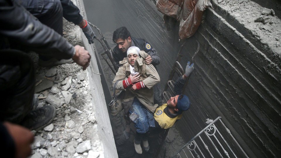 Syria Civil Defence members help an unconscious woman from a shelter in the besieged town of Douma, Eastern Ghouta, Damascus, on February 22, 2018. 