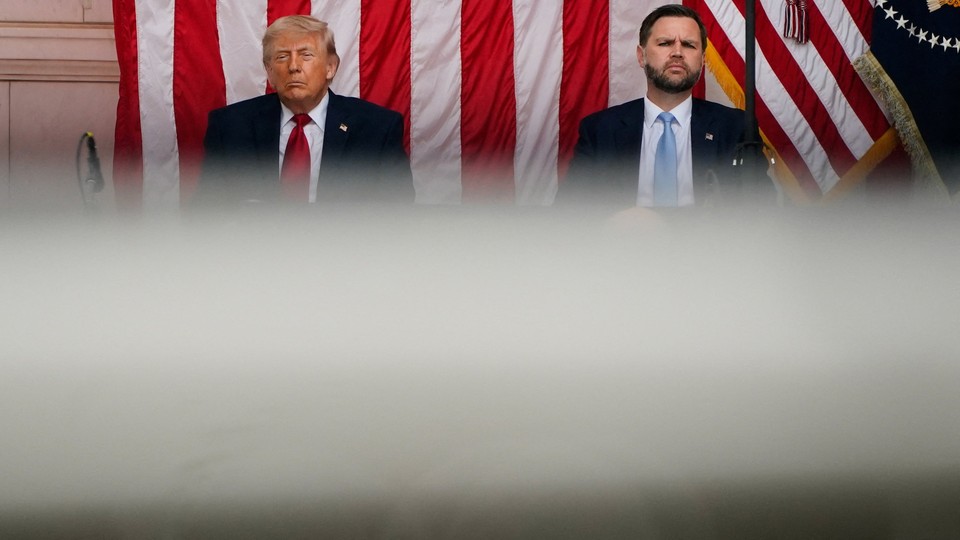 A photograph of Donald Trump and J. D. Vance sitting next to each other in front of a large American flag.